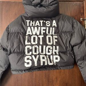 This is a black cropped puffer jacket from the brand Awful Lot Of Cough Syrup.